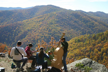 five band members playing music with blue ridge mountains in the background